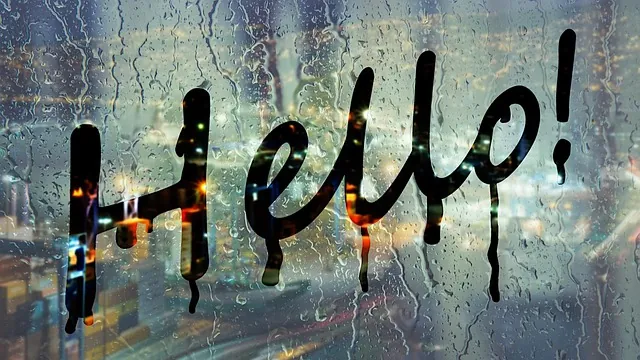 Palabra «Hello!» sobre un cristal con gotas de lluvia